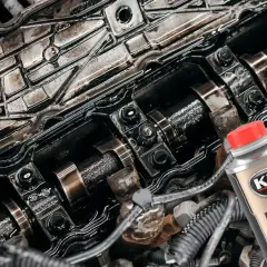 Brudny silnik czeka na płukanie. Butelka K2 Motor Flush z czerwoną nakrętką sugeruje odświeżenie.