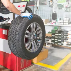 Mechanik w warsztacie sprawdza wyważenie koła z felgami nieprzelotowymi na maszynie.