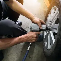 Mechanik używa klucza pneumatycznego do wymiany wentyla w oponie samochodu.