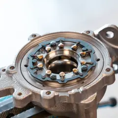 Metalowa obudowa turbosprężarki ze zmienną geometrią, z widocznym mechanizmem łopatek i elementami mocującymi.
