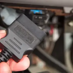 Ręka trzyma adapter OBD II, gotowy do odczytu kodów błędów obd po polsku i diagnozy auta.