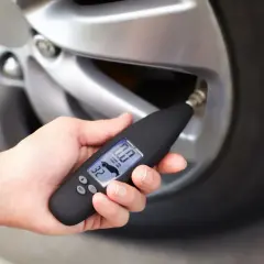 Dłoń trzyma miernik ciśnienia, który pokazuje 0.0 PSI. Wygląda na to, że uszkodzony czujnik ciśnienia w oponach uniemożliwia odczyt.