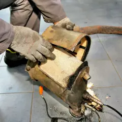 Mechanik w rękawiczkach rozkłada zapchany filtr DPF, przygotowując go do wypalania.