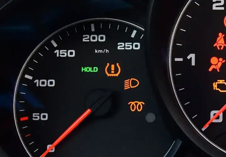 Na desce rozdzielczej świeci się kontrolka systemu TPMS, informując o niskim ciśnieniu w oponach. Obok świeci się zielona kontrolka HOLD.