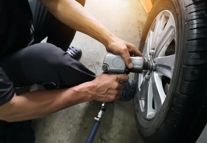 Mechanik używa klucza pneumatycznego do wymiany wentyla w oponie samochodu.