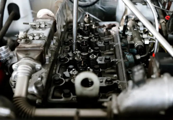 Widok wnętrza silnika z widocznymi zaworami i wtryskiwaczami. Mechanik sprawdza, czy nie ma stukania w silniku.