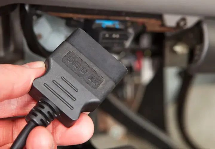 Ręka trzyma adapter OBD II, gotowy do odczytu kodów błędów obd po polsku i diagnozy auta.