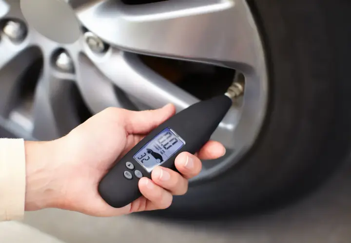 Dłoń trzyma miernik ciśnienia, który pokazuje 0.0 PSI. Wygląda na to, że uszkodzony czujnik ciśnienia w oponach uniemożliwia odczyt.