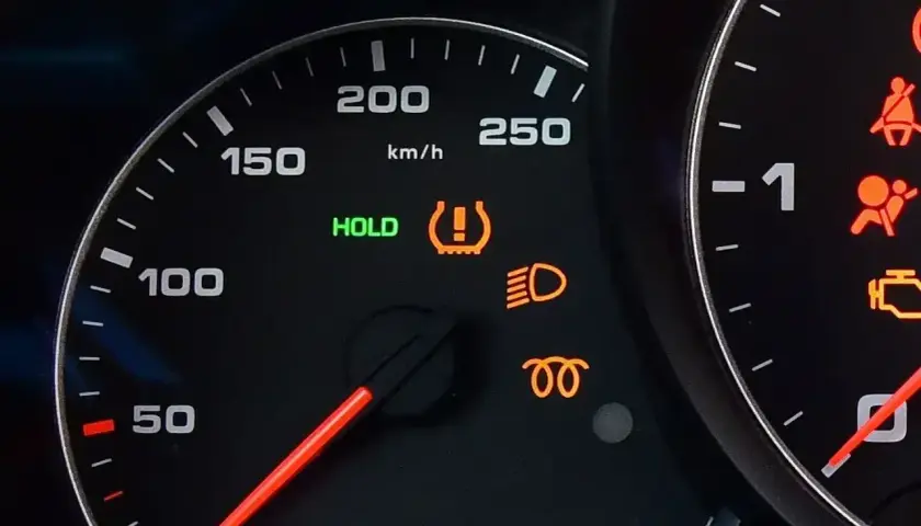 Na desce rozdzielczej świeci się kontrolka systemu TPMS, informując o niskim ciśnieniu w oponach. Obok świeci się zielona kontrolka HOLD.