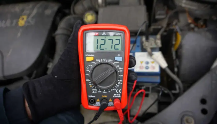 Jak sprawdzić napięcie miernikiem w samochodzie? Oto wynik 12.72V na wyświetlaczu multimetru, podłączonego do akumulatora.