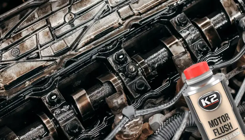 Brudny silnik czeka na płukanie. Butelka K2 Motor Flush z czerwoną nakrętką sugeruje odświeżenie.