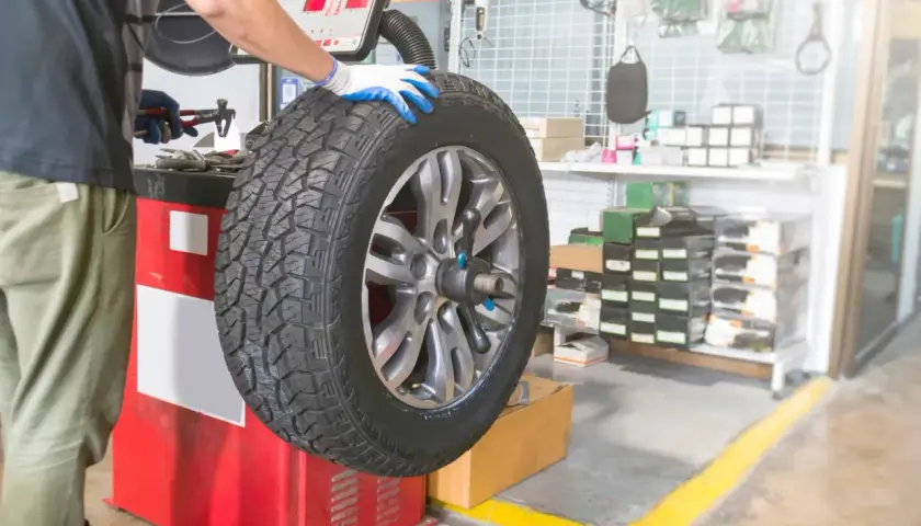 Mechanik w warsztacie sprawdza wyważenie koła z felgami nieprzelotowymi na maszynie.