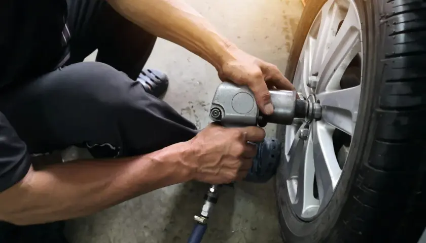 Mechanik używa klucza pneumatycznego do wymiany wentyla w oponie samochodu.