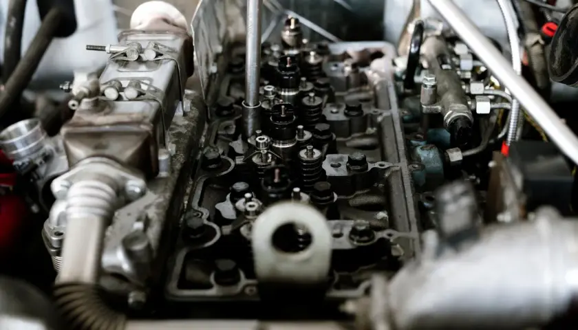 Widok wnętrza silnika z widocznymi zaworami i wtryskiwaczami. Mechanik sprawdza, czy nie ma stukania w silniku.