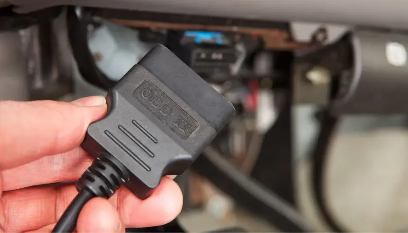 Ręka trzyma adapter OBD II, gotowy do odczytu kodów błędów obd po polsku i diagnozy auta.