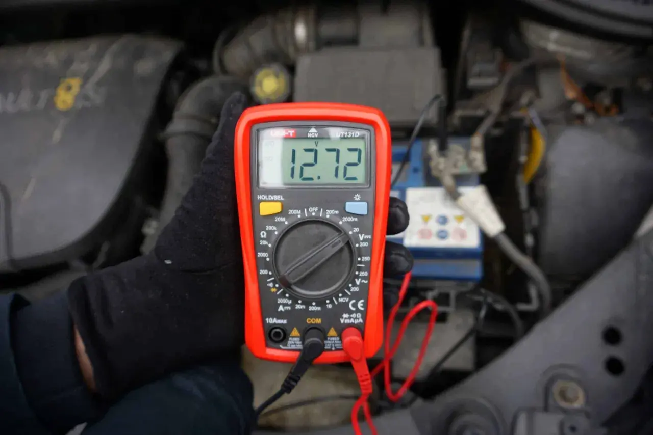Jak sprawdzić napięcie miernikiem w samochodzie? Oto wynik 12.72V na wyświetlaczu multimetru, podłączonego do akumulatora.