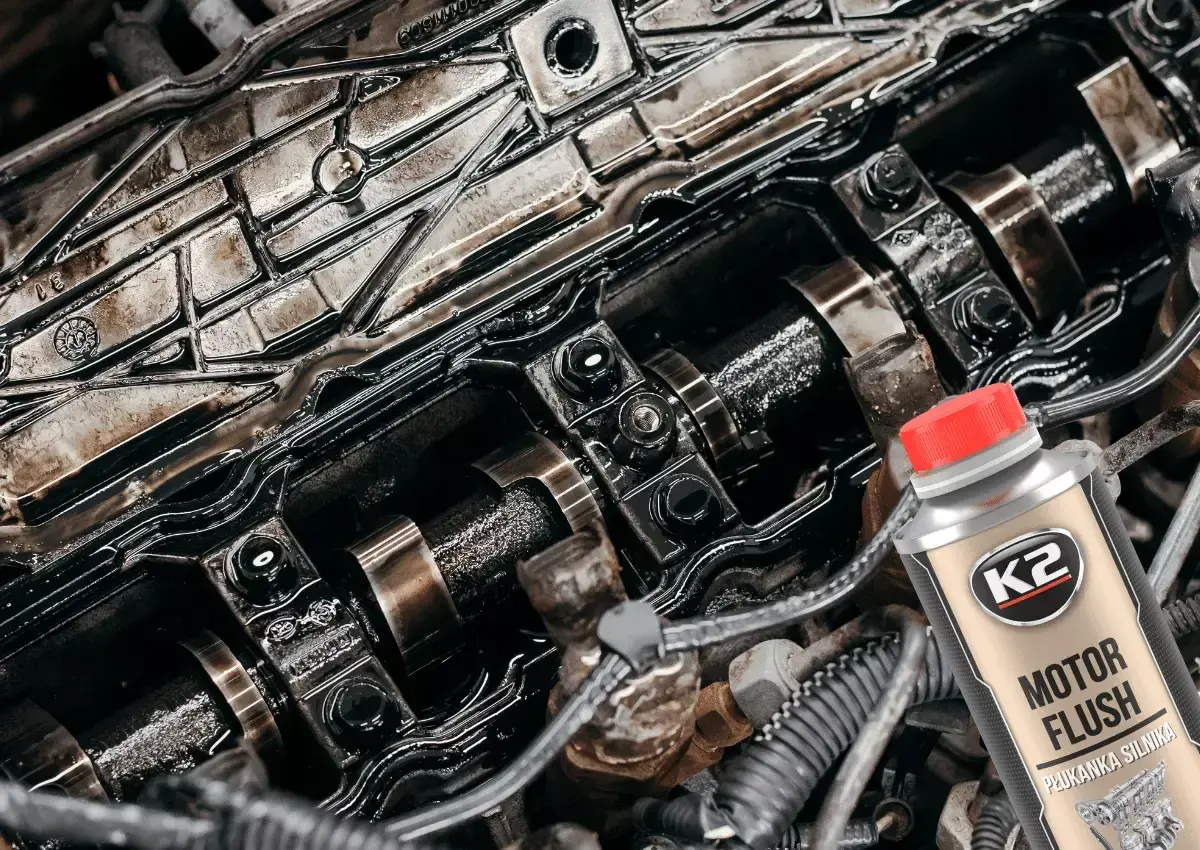 Brudny silnik czeka na płukanie. Butelka K2 Motor Flush z czerwoną nakrętką sugeruje odświeżenie.