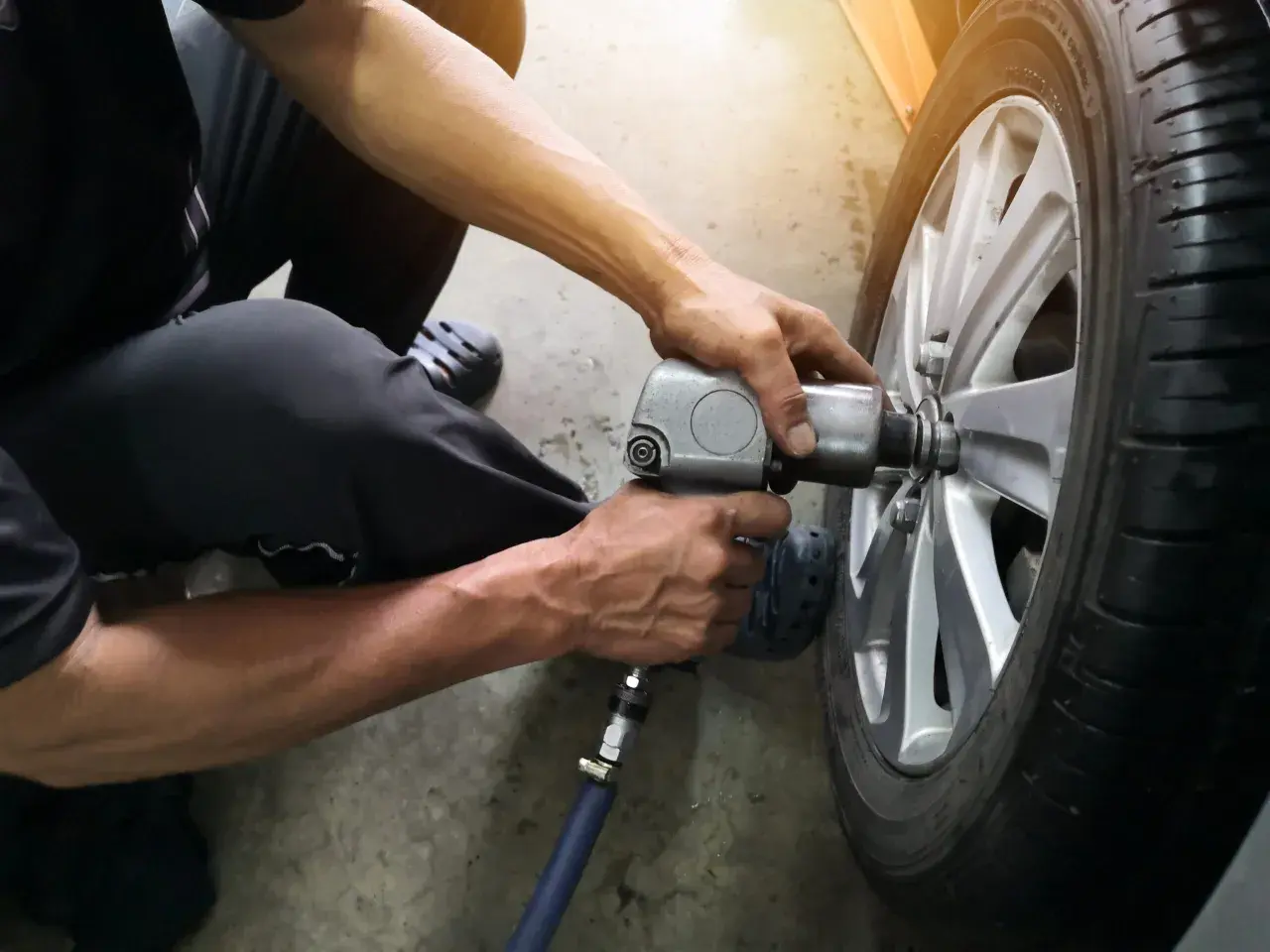 Mechanik używa klucza pneumatycznego do wymiany wentyla w oponie samochodu.
