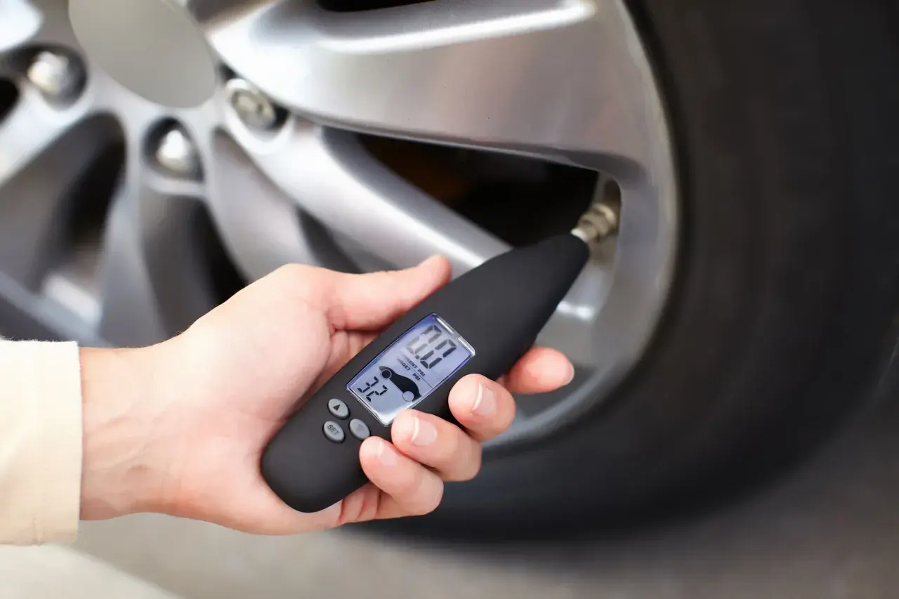 Dłoń trzyma miernik ciśnienia, który pokazuje 0.0 PSI. Wygląda na to, że uszkodzony czujnik ciśnienia w oponach uniemożliwia odczyt.