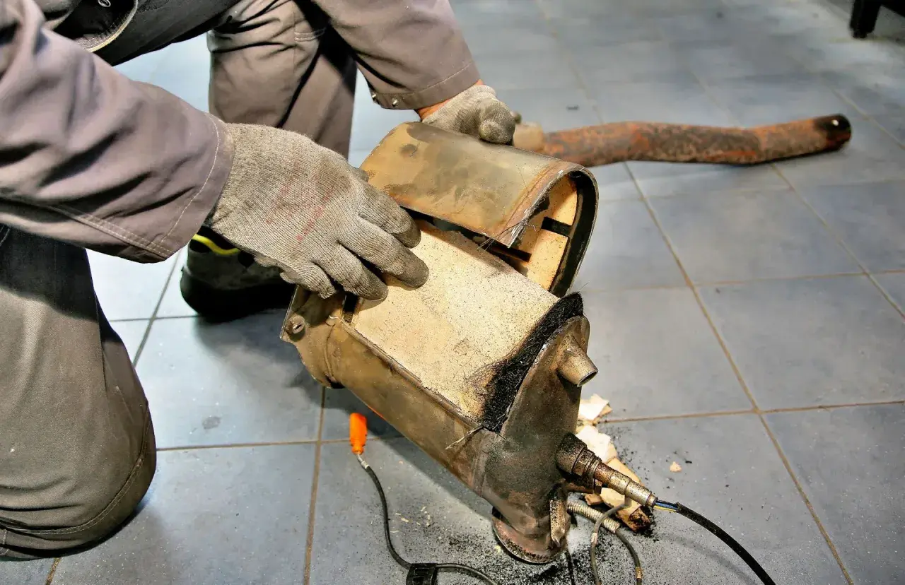 Mechanik w rękawiczkach rozkłada zapchany filtr DPF, przygotowując go do wypalania.
