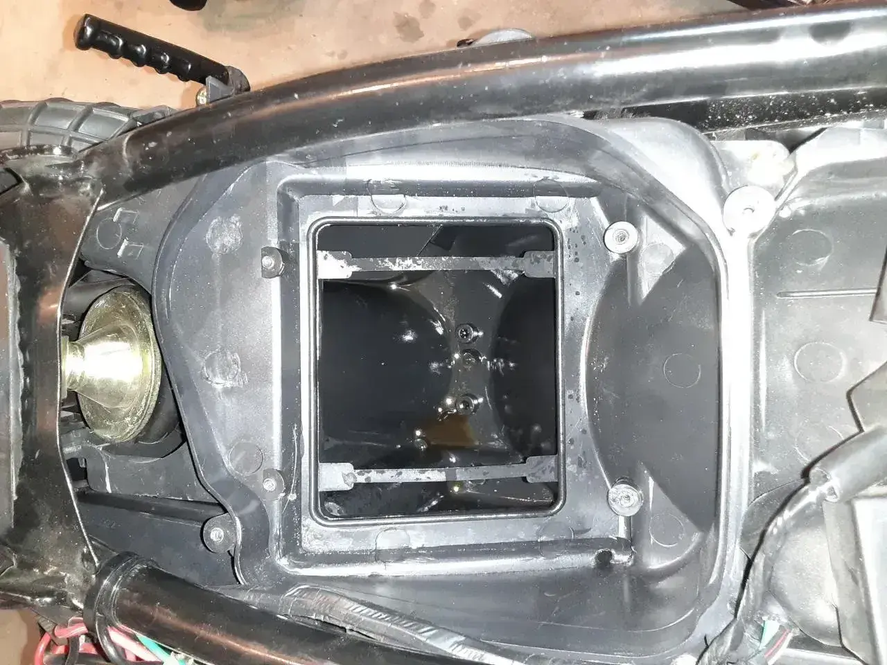 W obudowie filtra powietrza motocykla widać ciemny olej w odmie.