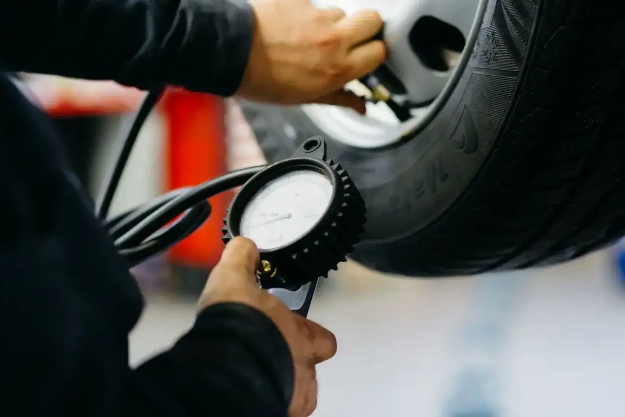 Mechanik sprawdza ciśnienie w oponie za pomocą manometru, dbając o prawidłowe działanie systemu TPMS.