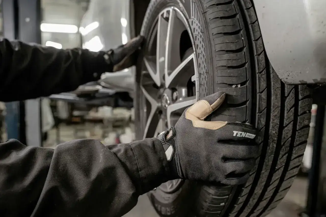 Mechanik w rękawiczkach sprawdza oponę, szukając uszkodzeń. Profesjonalna naprawa opon to klucz do bezpiecznej jazdy.
